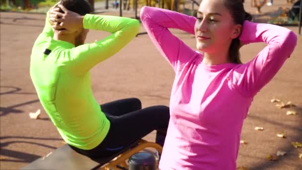 Belle fille en forme avec partenaire masculin travaillant sur un terrain de sport en automne — Video