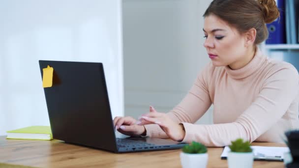 Femme d'affaires sérieuse assise au bureau et tapant sur un ordinateur portable — Video