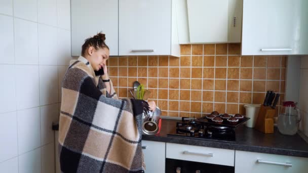 Девочка-подросток разговаривает по телефону и пьет чай в одиночестве дома — стоковое видео