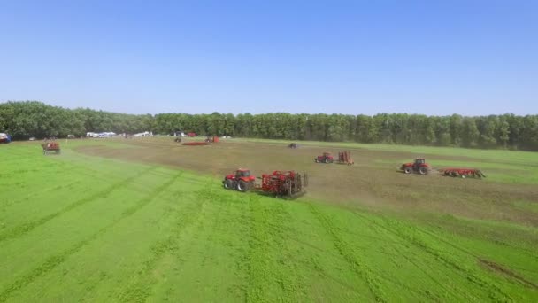 Trattori agricoli per la coltivazione e la raccolta di colture a cavallo su campi verdi — Video Stock