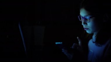 Geceleri akıllı telefon ve laptop kullanan bağımlı bir çocuk.