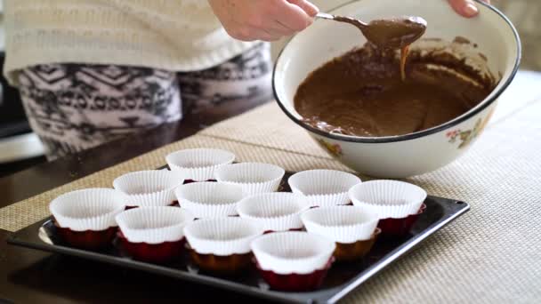 Erntefrau füllt Cupcake-Papier-Formulare mit Schokoladenteig — Stockvideo