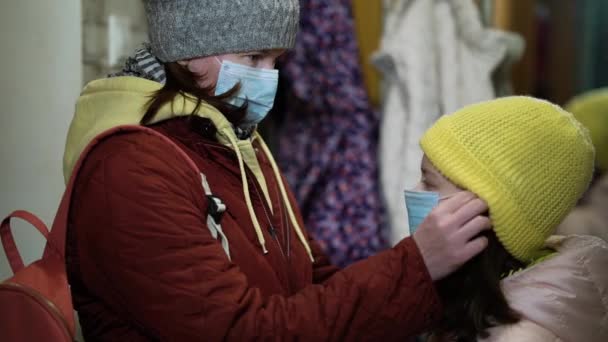 Mãe cuidando da filha e colocando máscara nela antes de sair de casa — Vídeo de Stock