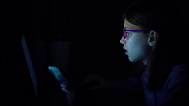 Niño adicto usando teléfono inteligente y portátil por la noche — Vídeos de Stock