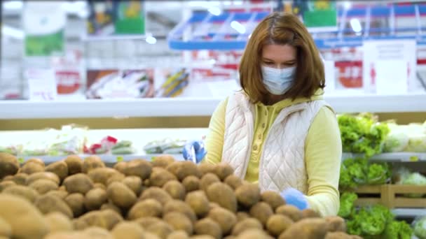 Chica en máscara recogiendo patatas en el departamento de verduras en la tienda de comestibles — Vídeo de stock