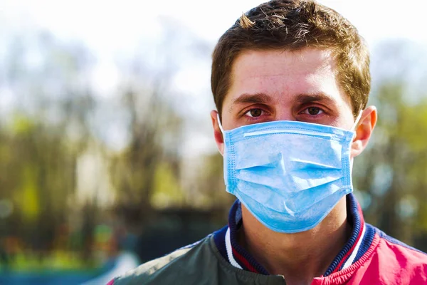 Park 'ta tıbbi maske takan genç bir adamın portresi.