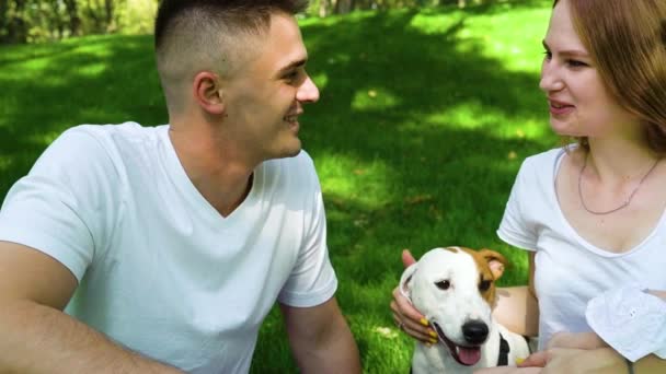 Обаятельная семья с ребенком и собакой Джек Рассел Терьер отдыхает в парке — стоковое видео