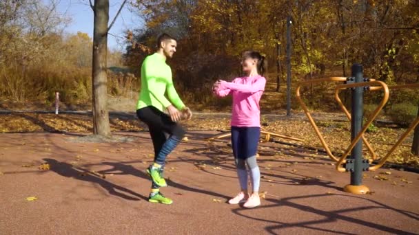 Famille athlétique étirant les jambes sur le terrain de sport par une journée ensoleillée en automne — Video