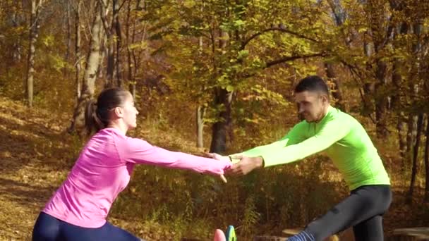 Young family holding hands and exercising in autumn forest — Stock Video