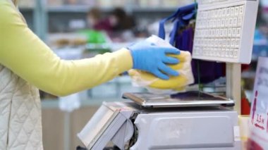 Süpermarkette muz tartan tek kullanımlık eldivenli bir kadın.