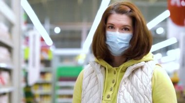 Salgın sırasında alışveriş merkezinde poz veren maskeli genç bir kadın.