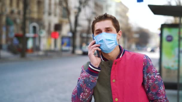 Junger Mann mit medizinischer Maske ruft Taxi nach draußen — Stockvideo