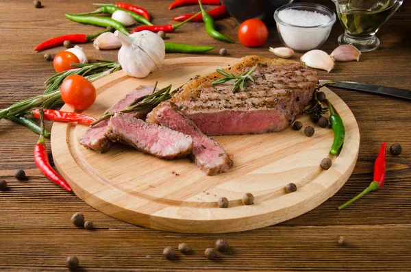 Rare steak wooden cutting board pepper rosemary — Stock Photo, Image