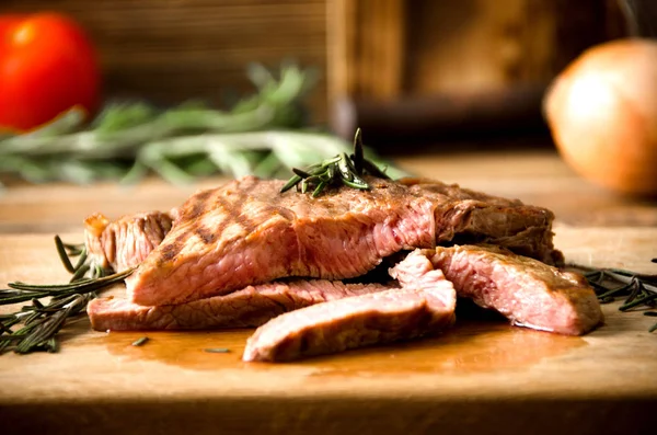 Rare steak rosemary rectangular wooden cutting board pepper — Stock Photo, Image