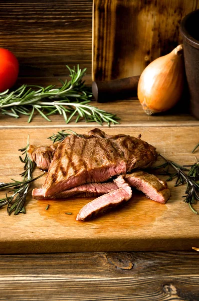 Rare steak rosemary rectangular wooden cutting board spices — Stock Photo, Image