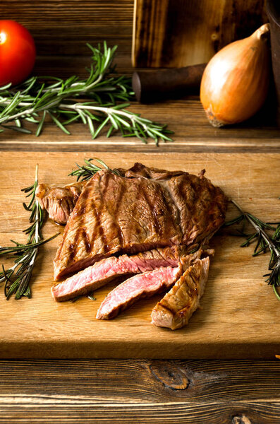 Rare steak sliced wooden cutting board spices on a brown wooden background