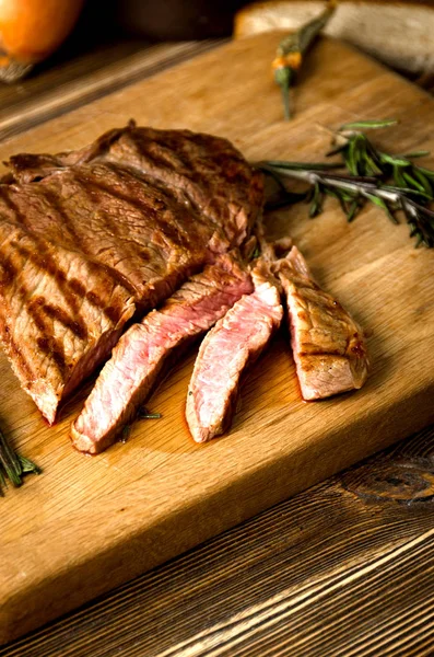 Rare steak rosemary sliced wooden cutting board pepper — Stock Photo, Image