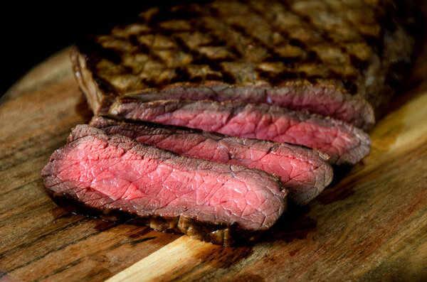 Rare steak wooden cutting board on a dark background