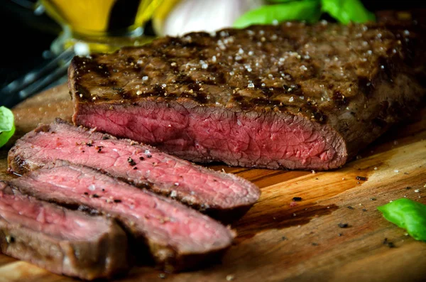 Sliced rare steak pepper garlic cutting board — Stock Photo, Image