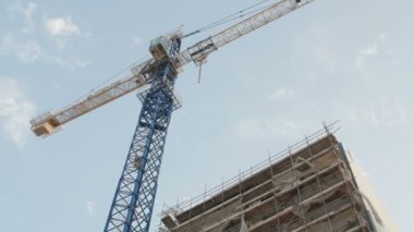 Mavi gökyüzüne karşı inşaat halindeki vinç ve bina
