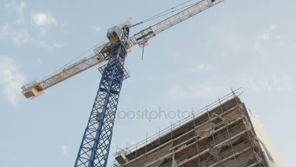 Gru e edificio in costruzione contro il cielo blu — Video Stock