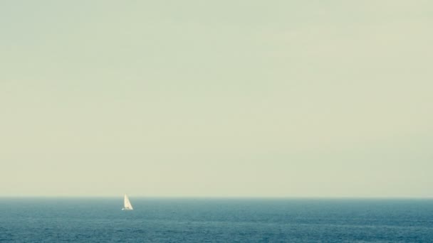 Bílá plachta jachta daleko na obzoru nad mořem. — Stock video