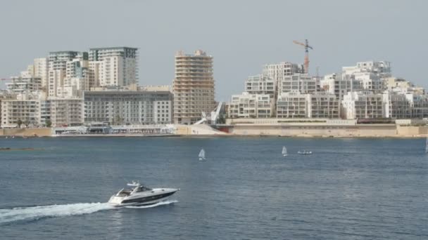 Barca, Yacht naviga sullo sfondo della città di La Valletta a Malta. Ampia ripresa, sullo sfondo di case di nuova costruzione . — Video Stock