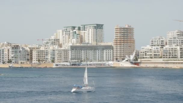 Tekne, yat şehir Malta Valletta arka planda yola çıkacak. Atış, yeni inşa edilmiş evlerin arka planda geniş. — Stok video