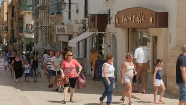 CENTRO DE LA CIUDAD DE MALTA CAPITAL VALLETTA, CALLE PEDESTRIANO - JULIO 2016: Muchas personas turísticas y locales de compras en el centro antiguo lleno de tiendas, cafetería, farmacia niños jugando, amigos charlando — Vídeo de stock