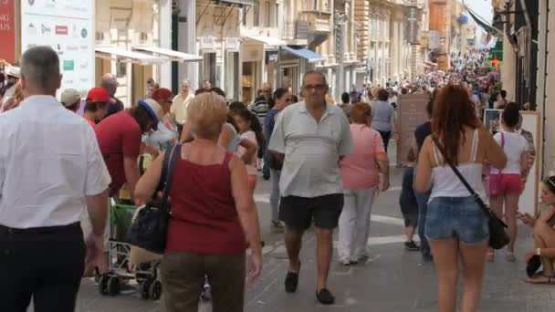 CENTRO DE LA CIUDAD DE MALTA CAPITAL VALLETTA, CALLE PEDESTRIANO - JULIO 2016: Muchas personas turísticas y locales de compras en el centro antiguo lleno de tiendas, cafetería, farmacia niños jugando, amigos charlando — Vídeo de stock