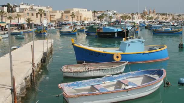 Marsaxlokk, Malta - 6 juli 2016: Prachtige visserij dorp architectuur met gekleurde boten op anker in een baai — Stockvideo