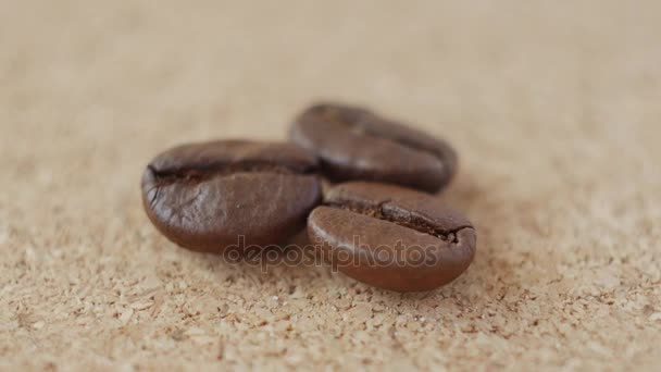 Three grains of coffee close-up on brown background. — Stock Video