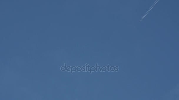 Fliegendes Flugzeug hinterlässt Kondensstreifen am blauen Himmel. — Stockvideo