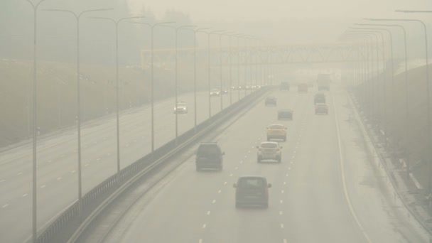 Automóviles coches conducen por la nebulosa carretera de la ciudad. Condiciones de conducción peligrosas en temporada de invierno . — Vídeo de stock