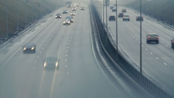 Automóveis carros dirigem na estrada nebulosa da cidade. Condições de condução perigosas na época de Inverno . — Vídeo de Stock