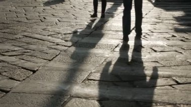 Kaldırım taşı kaldırım üzerinde insan siluetleri.