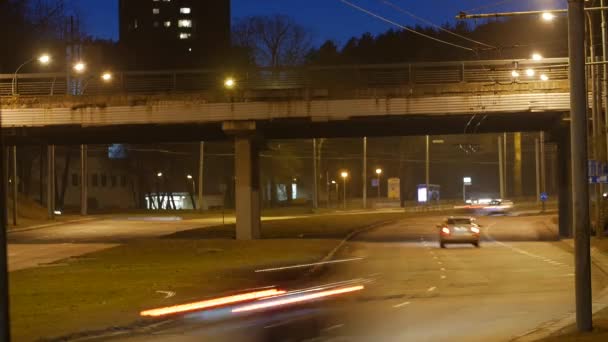 Časová prodleva, světelné stopy městské dopravy na pozadí budovy. — Stock video