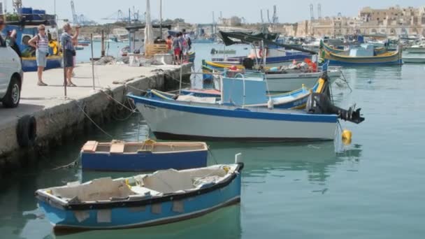 Marsaxlokk, Malta - 6 juli 2016: Prachtige visserij dorp architectuur met gekleurde boten op anker in een baai — Stockvideo