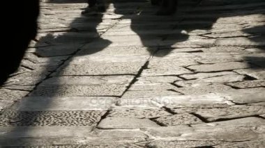 Kaldırım taşı kaldırım üzerinde insan siluetleri.
