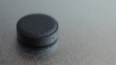 Aktif kömür tablet, metalik arka plan üzerinde izole.