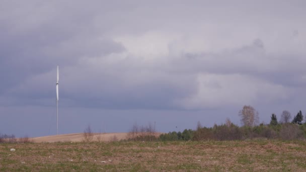 Větrná turbína v zeleném poli temnými mraky na jaře. — Stock video