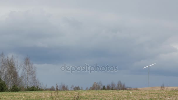 Ветряная турбина в зеленом поле с темными облаками весной . — стоковое видео