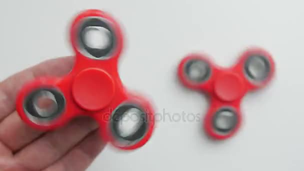 Close up footage of a persons hand playing with the fidget spinner, isolated on a white background — Stock Video