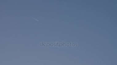 Jet uçağı buharı iz bırakarak mavi gökyüzünde uçar.