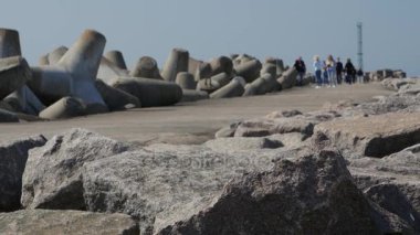 Turistler ve ziyaretçiler Klasipeda liman girişinde kayalara iskelesi ve dalgakıran yürüyüş.