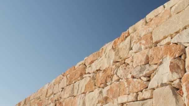 Un fragmento de una pared de piedra amarilla sobre un fondo azul del cielo — Vídeo de stock