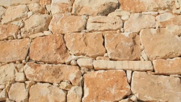 Un fragmento de una pared de piedra amarilla sobre un fondo azul del cielo — Vídeos de Stock