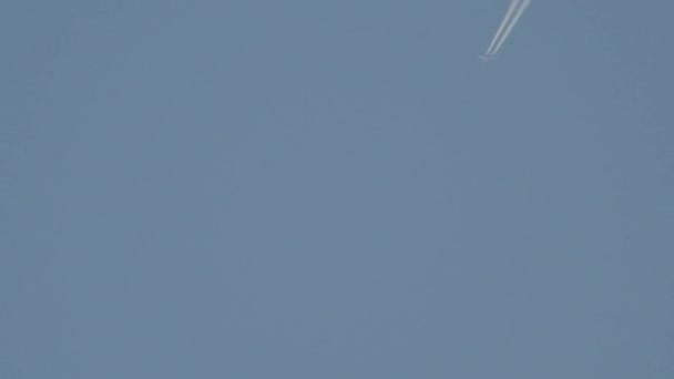 Реактивный самолет со следами на голубом небе — стоковое видео
