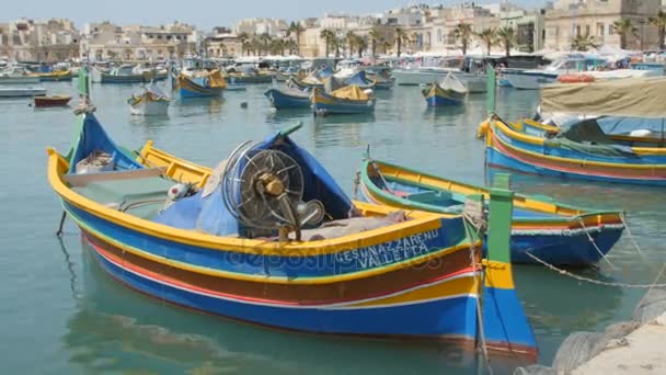 Marsaxlokk, Malta - 6 juli 2016: Prachtige visserij dorp architectuur met gekleurde boten op anker in een baai — Stockvideo