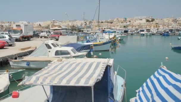 Marsaxlokk, Malta - 6 juli 2016: Prachtige visserij dorp architectuur met gekleurde boten op anker in een baai — Stockvideo